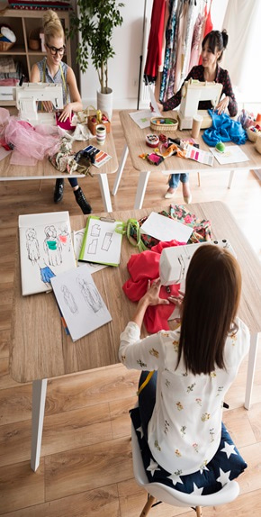 three girls sitting in a tailoring class